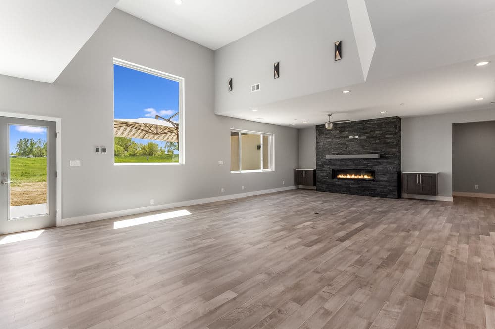Spacious modern living room with stone fireplace and large windows for natural light.