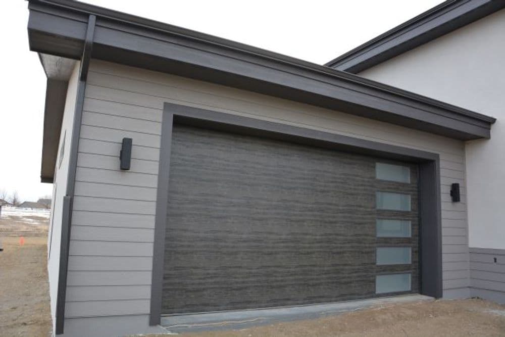 Modern home exterior with a sleek gray garage door and contemporary siding.